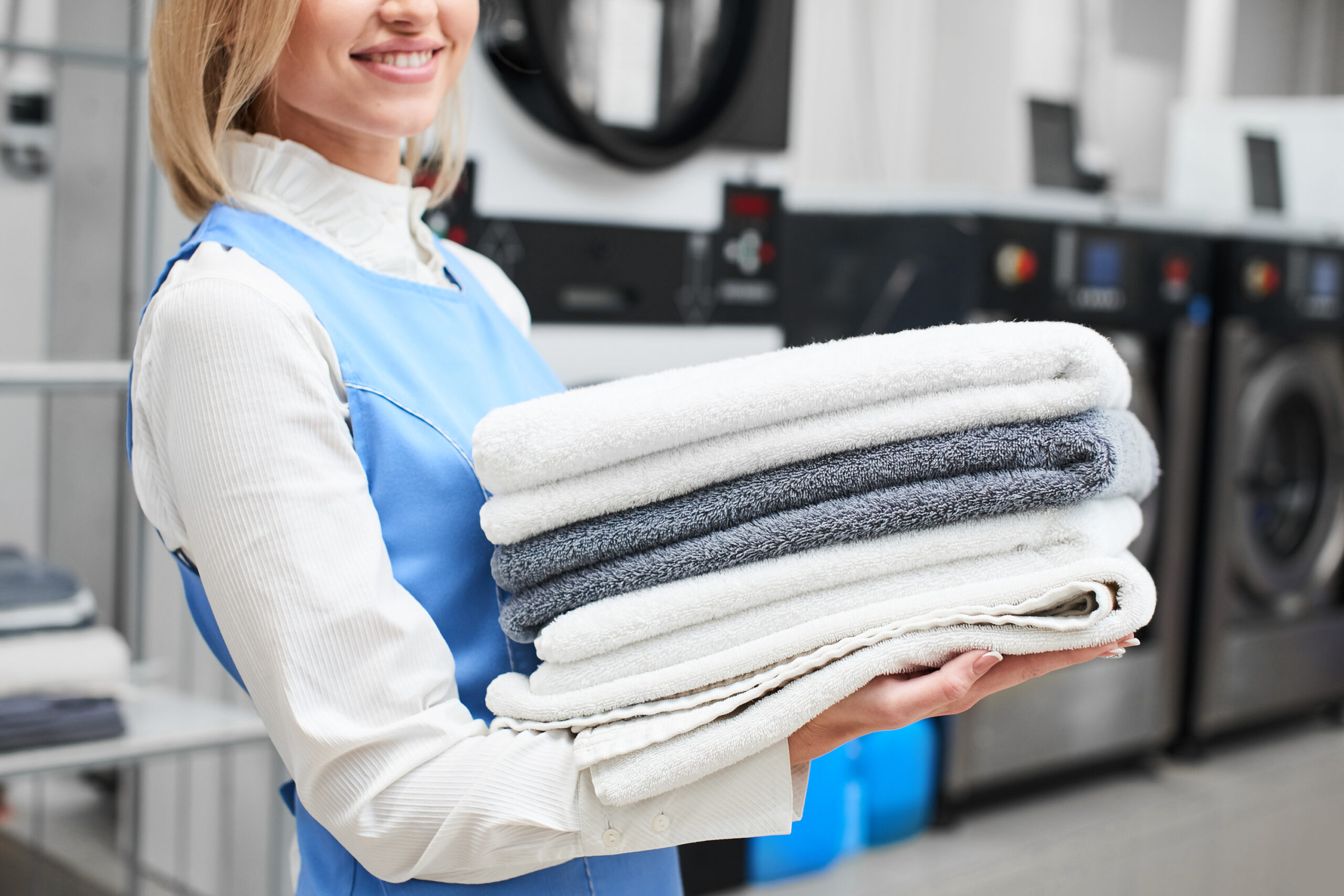 Portrait of a laundry worker on the background of clothes on hangers in dry cleaning